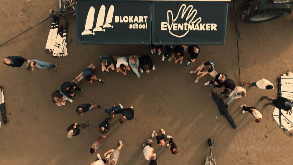 Bovenaanzicht van deelnemers die blokart-instructie volgen bij het base camp op het strand van IJmuiden
