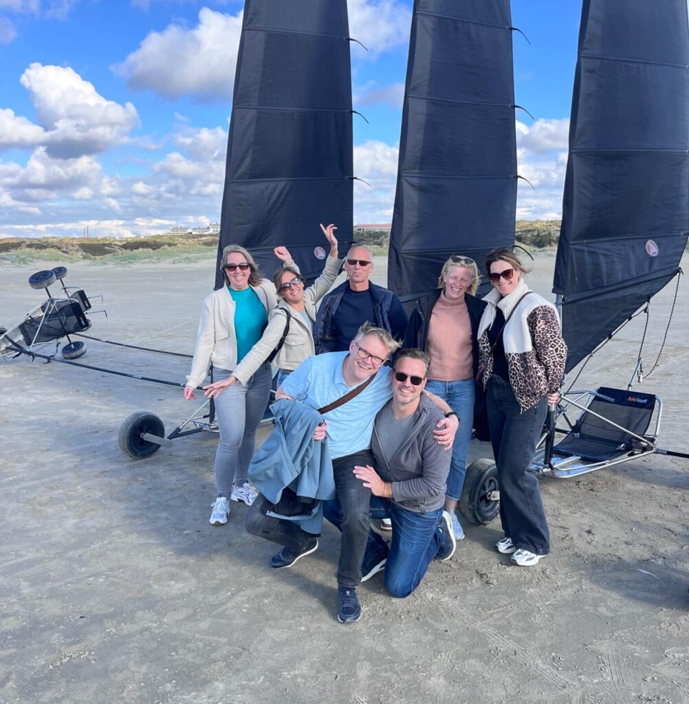 Groepsfoto van mannen en vrouwen van een bedrijf na een geslaagd bedrijfsuitje blokarten op het strand