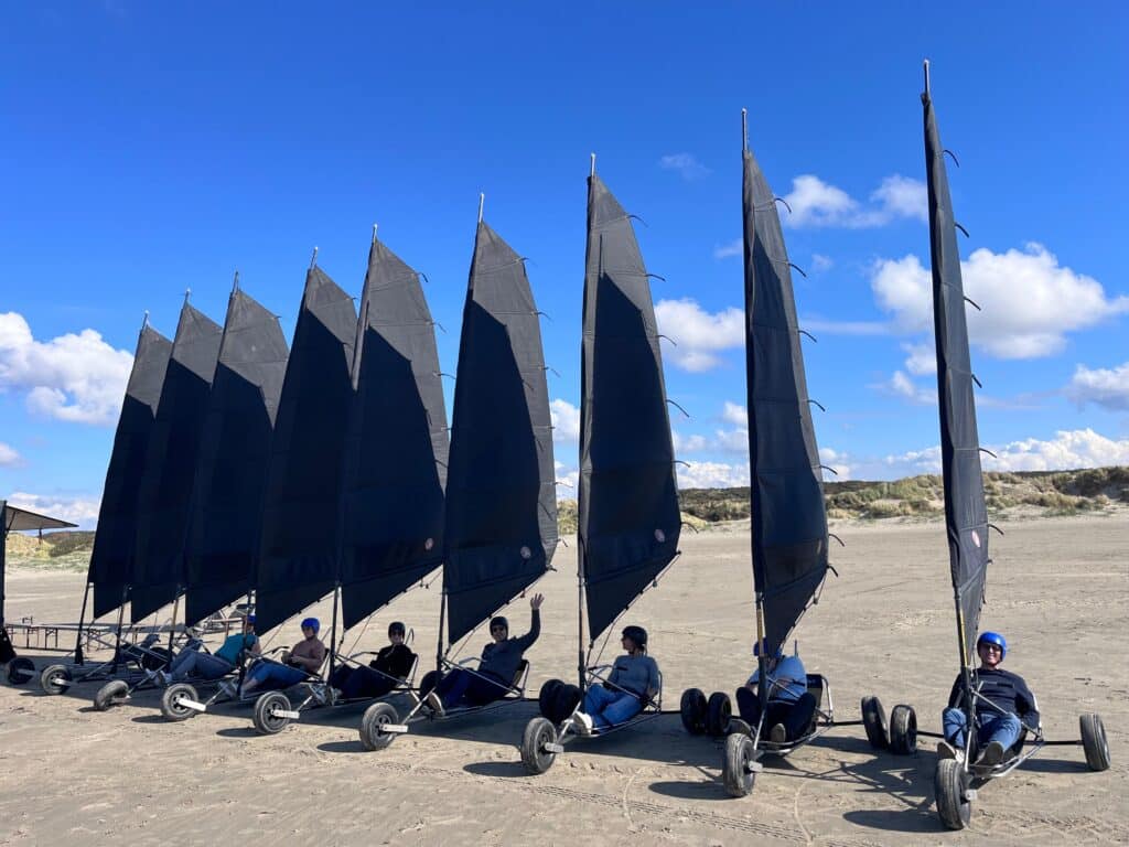 Groep vrienden zwaait in een blokart vlak voor vertrek tijdens een premium extend groepsuitje blokarten bij de Zuidpier