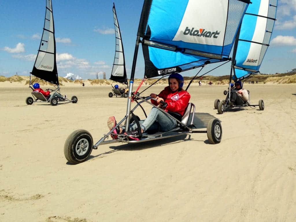 Vrouw rijdt vol gas blokart op zonnig Kennemerstrand bij blokarten IJmuiden