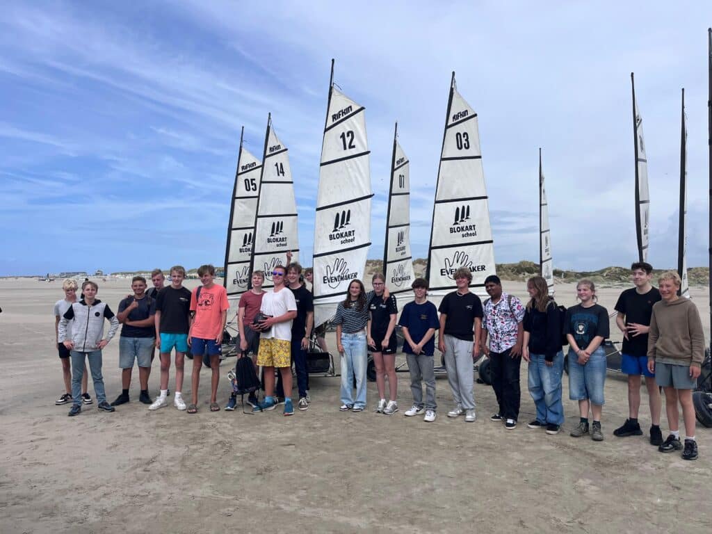 Groep kinderen van 7 tot 14 jaar en gezin na een geslaagde blokart sessie op het strand van IJmuiden